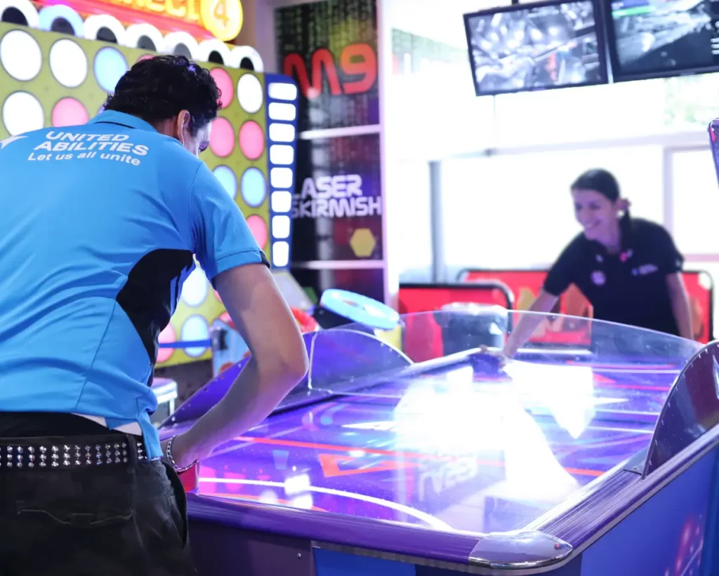 United Abilities client playing air hockey with a support worker